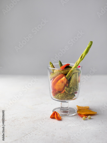 Dehydrated vegan chips in a wooden mango bowl. Vitamin healthy fast food with carrot slices, beetroot wedges, broccoli, zucchini on a light table. food photo banner copy space. photo