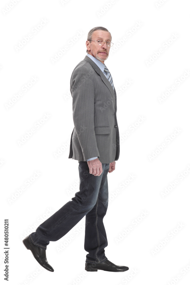 side view full length photo of a mid aged business man walking forward and looking at camera. side view full length photo of a mid aged business man walking forward and looking at camera.