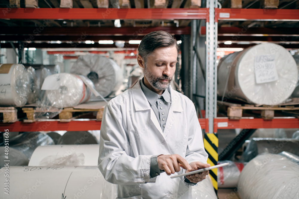 Man in white robe at factory shelves Man in white robe at factory shelves