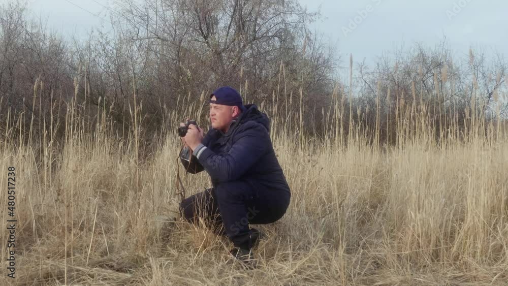 a man takes pictures near the reeds on a retro camera side view a man takes pictures near the reeds on a retro camera side view