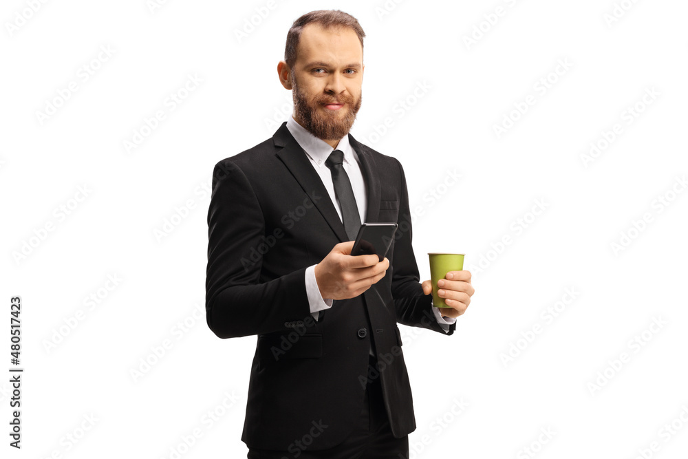 Young businessman holding a paper coffee cup and a mobile phone and looking at camera Young businessman holding a paper coffee cup and a mobile phone and looking at camera