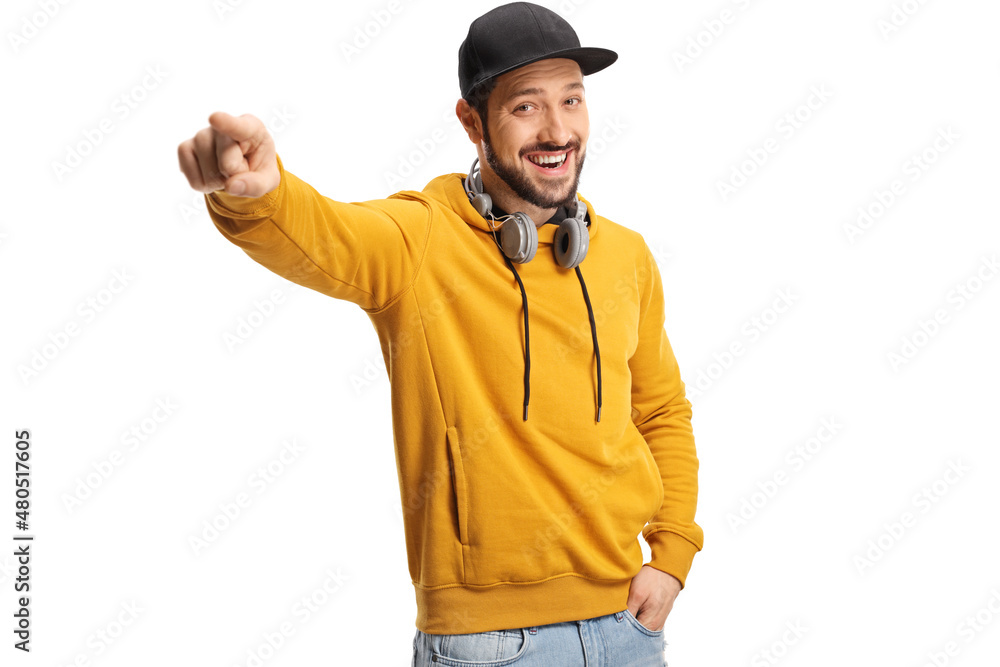 Smiling young man with headphones around neck and a cap pointing with finger Smiling young man with headphones around neck and a cap pointing with finger