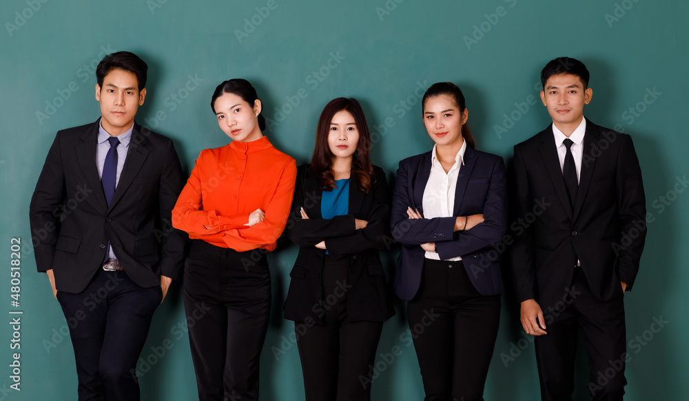 Obraz premium Portrait studio shot group of Asian professional male female teacher or college students in formal suit outfit standing crossed arms smiling look at camera on green chalkboard background in classroom