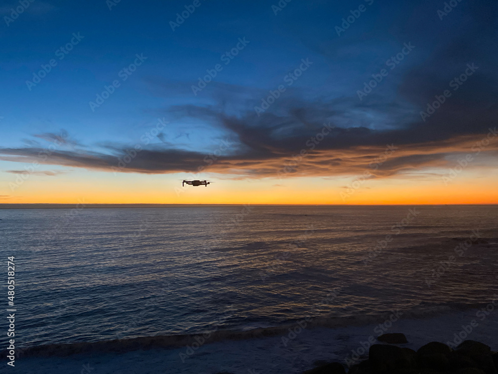 Drone flying over the ocean at sunset