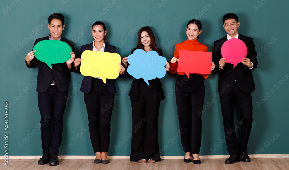 Portrait studio shot group of Asian professional male female teacher or college students in formal suit outfit standing smiling look at camera holding conversation sign on green chalkboard background