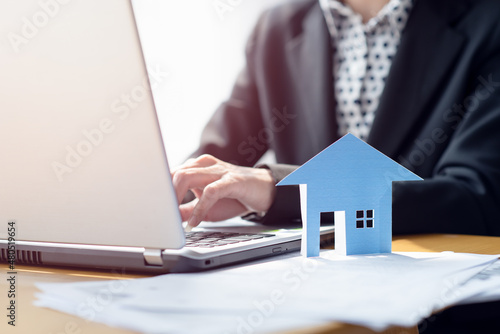 Close up of a businesswoman hands typing in a laptop in the office with paper house