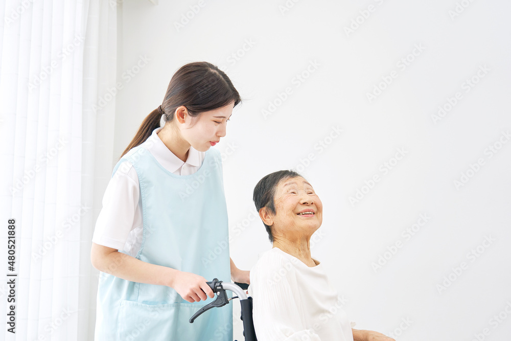 Obraz premium 車椅子に乗る高齢者と介護士 屋内
