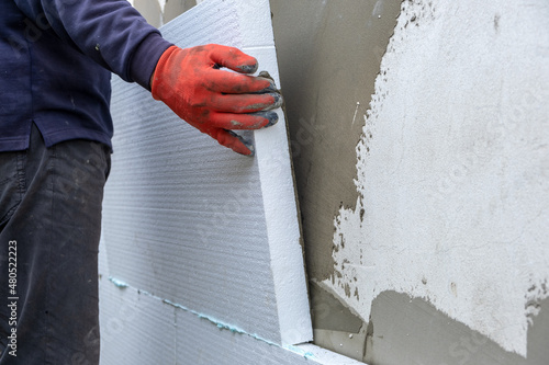 Billede på lærred Construction worker installing styrofoam insulation sheets on house facade wall