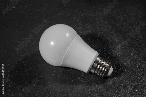 White LED light bulb on table with black background, photo for design