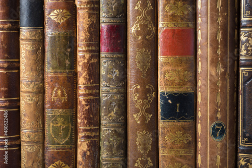 Old books, vintage book covers on bookshelf. Antique leather-bound book covers with golden ornament.