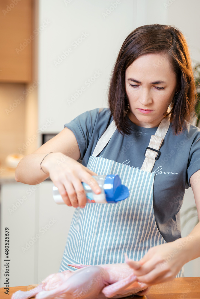 A woman in the kitchen sprinkles duck with salt. Cooking delicious duck for the holiday. A woman in the kitchen sprinkles duck with salt. Cooking delicious duck for the holiday.