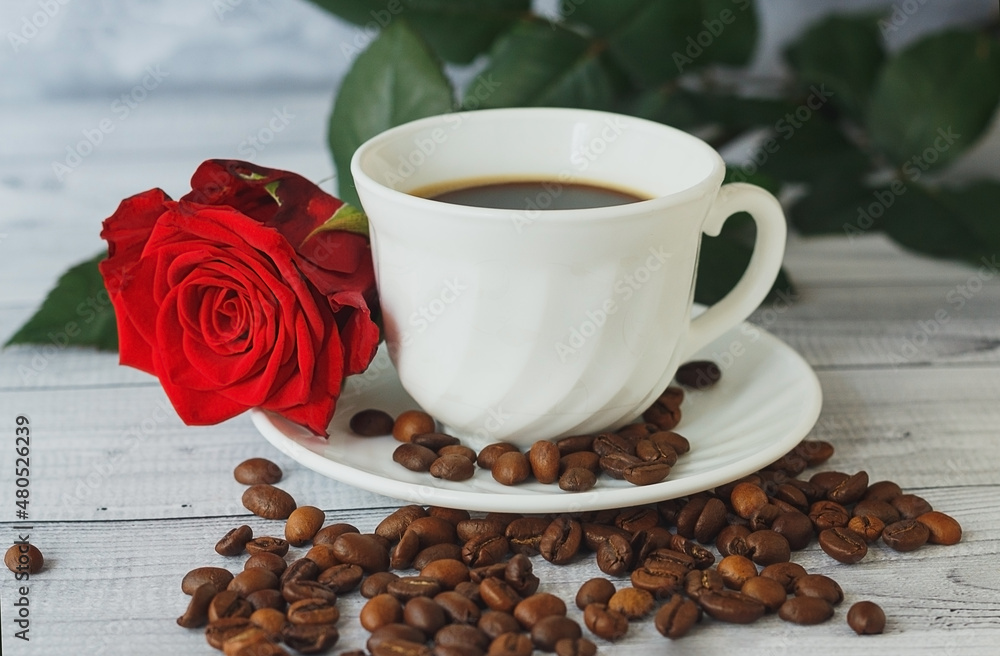 Obraz premium White cup of coffee, coffee beans and red roses on light gray background. Romantic breakfast concept.