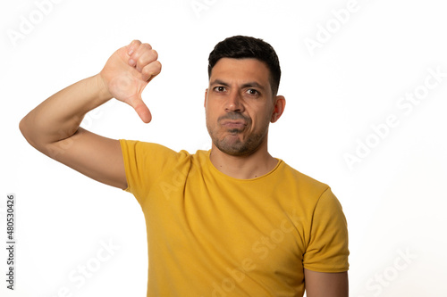 attractive young man in yellow t-shirt with thumb down. White background - Stock photo