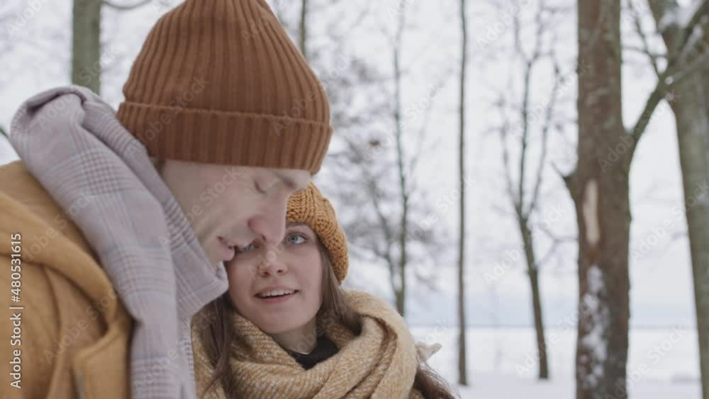 Medium close up with slowmo of young Caucasian couple with ski poles in hands spending weekend in winter forest together Medium close up with slowmo of young Caucasian couple with ski poles in hands spending weekend in winter forest together