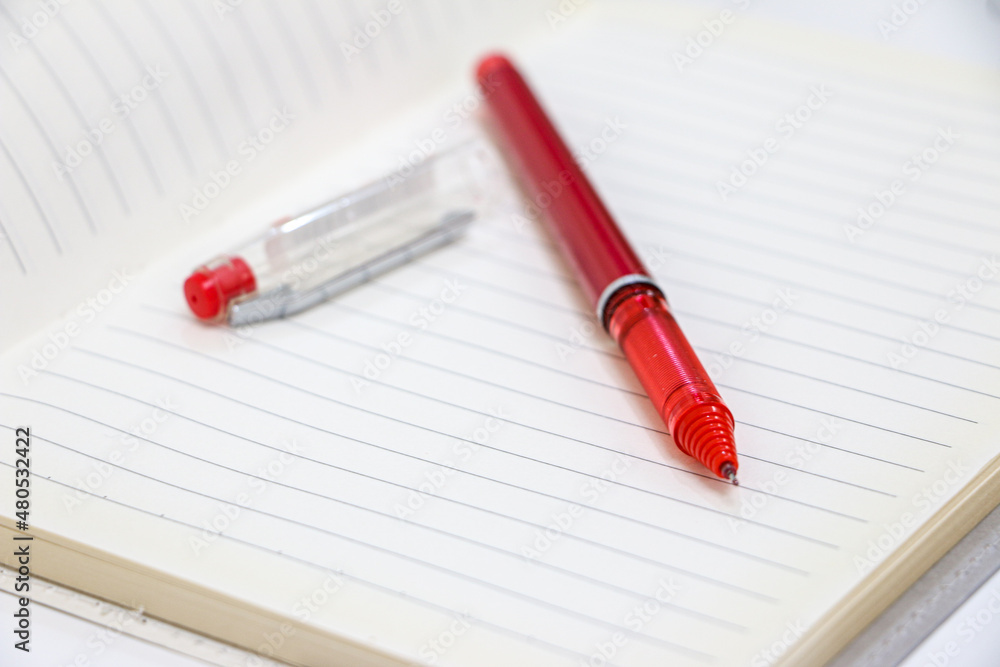 Red Pen and Pen Lid on a Blank Page of a Notebook Red Pen and Pen Lid on a Blank Page of a Notebook