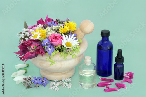Essential oil preparation for aromatherapy herbal plant medicine treatments. Herbs, flowers in a mortar and loose with almond oil for steeping. Natural alternative health and wellness concept. 