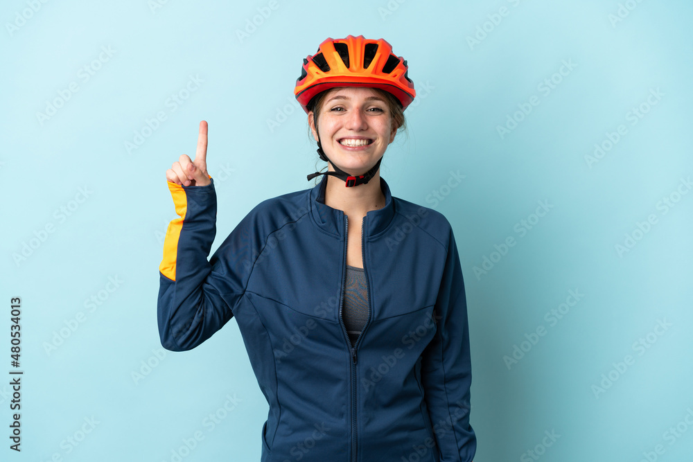 Young cyclist woman isolated on blue background pointing up a great idea Young cyclist woman isolated on blue background pointing up a great idea