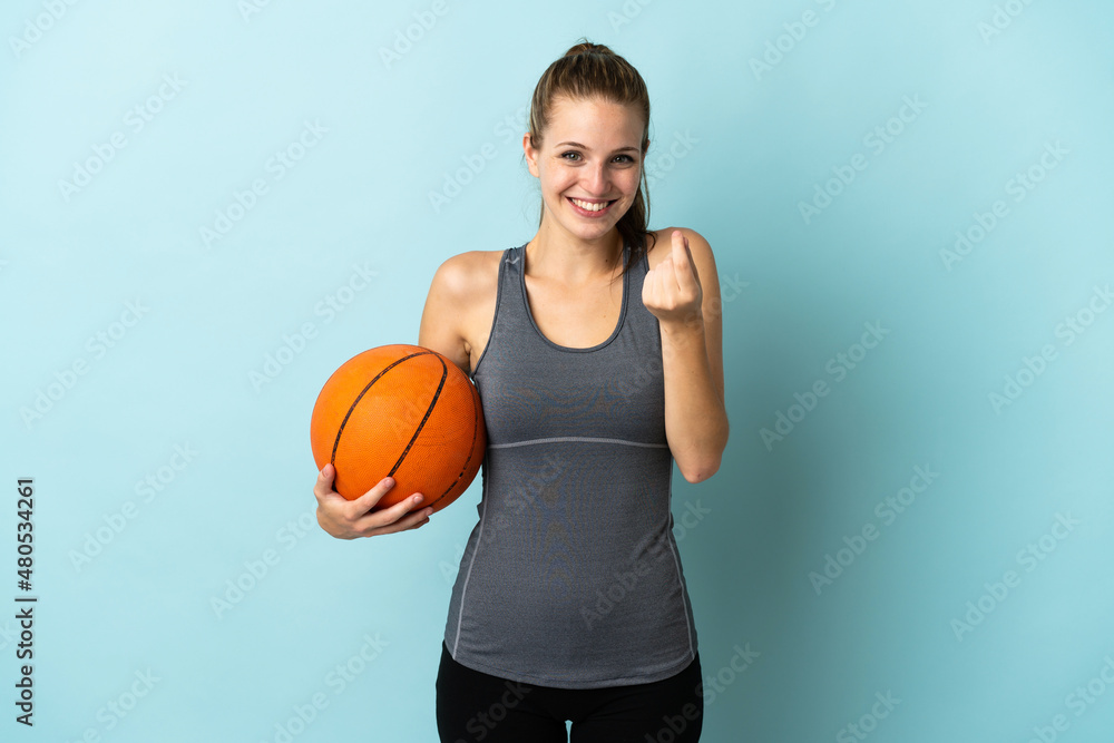 Naklejka premium Young woman playing basketball isolated on blue background making money gesture