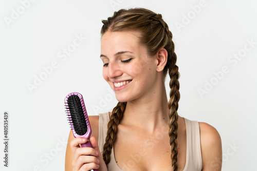Young caucasian woman isolated on white background with hair comb and looking it