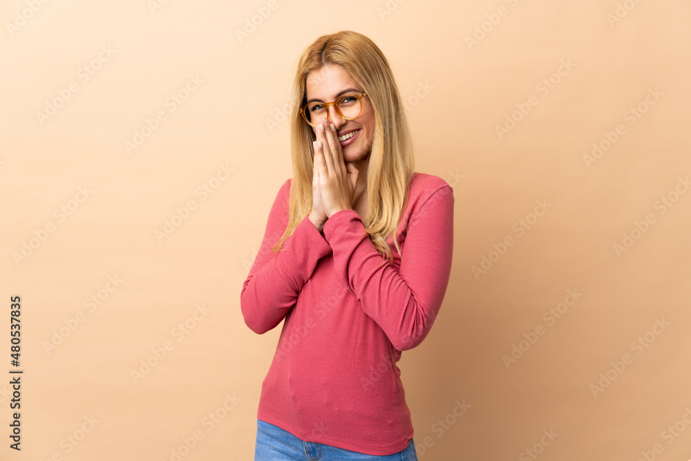 Young Uruguayan blonde woman over isolated background keeps palm together. Person asks for something Young Uruguayan blonde woman over isolated background keeps palm together. Person asks for something