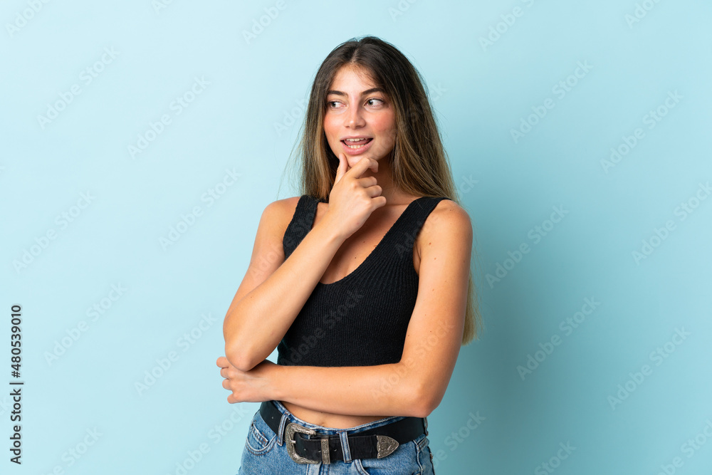 Young caucasian woman isolated on blue background looking to the side and smiling Young caucasian woman isolated on blue background looking to the side and smiling
