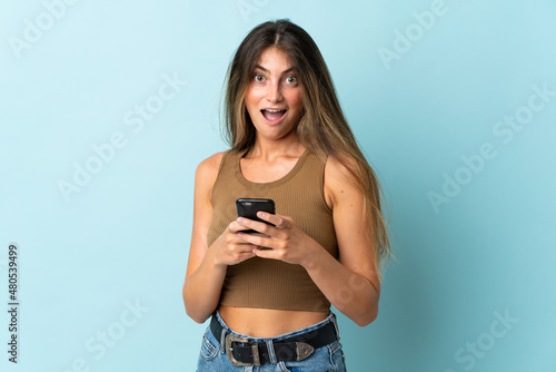 Young caucasian woman isolated on blue background surprised and sending a message