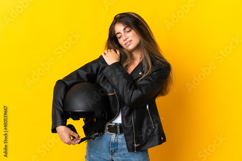 Woman holding a motorcycle helmet isolated on yellow background suffering from pain in shoulder for having made an effort
