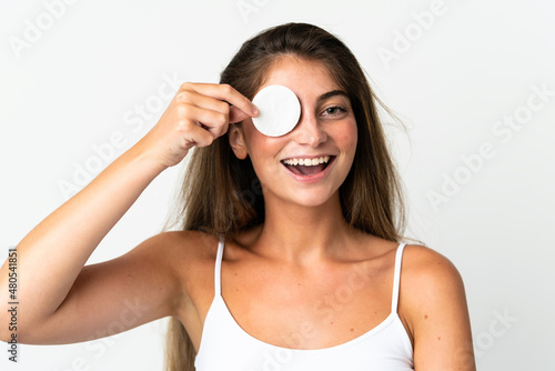 Young caucasian woman isolated on white background with cotton pad for removing makeup from her face and smiling