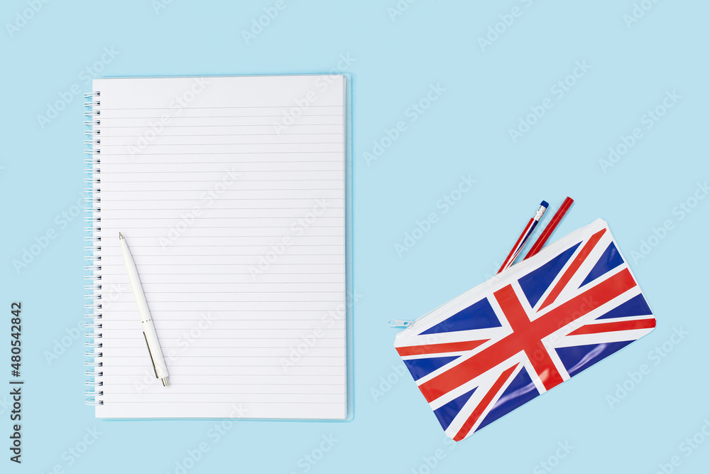 Fototapeta premium pencil case on desk with a pencil and a blank notebook and british english union jack flag. Flat lay with copy space. Education study or english language learning concept or travel and visa
