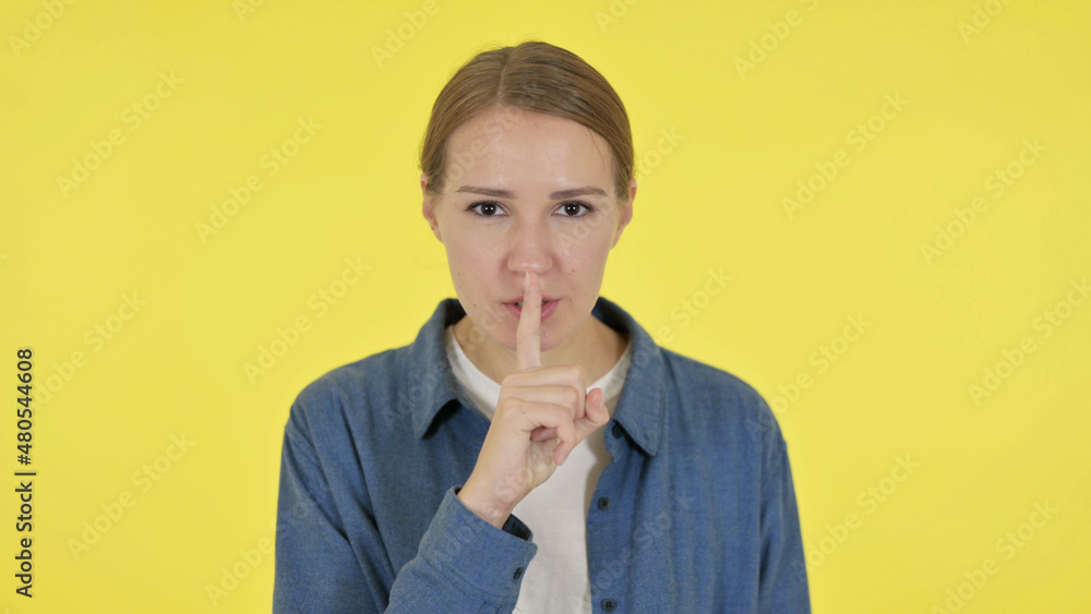 Young Woman with Finger on Lips, Silence Yellow Screen Young Woman with Finger on Lips, Silence Yellow Screen
