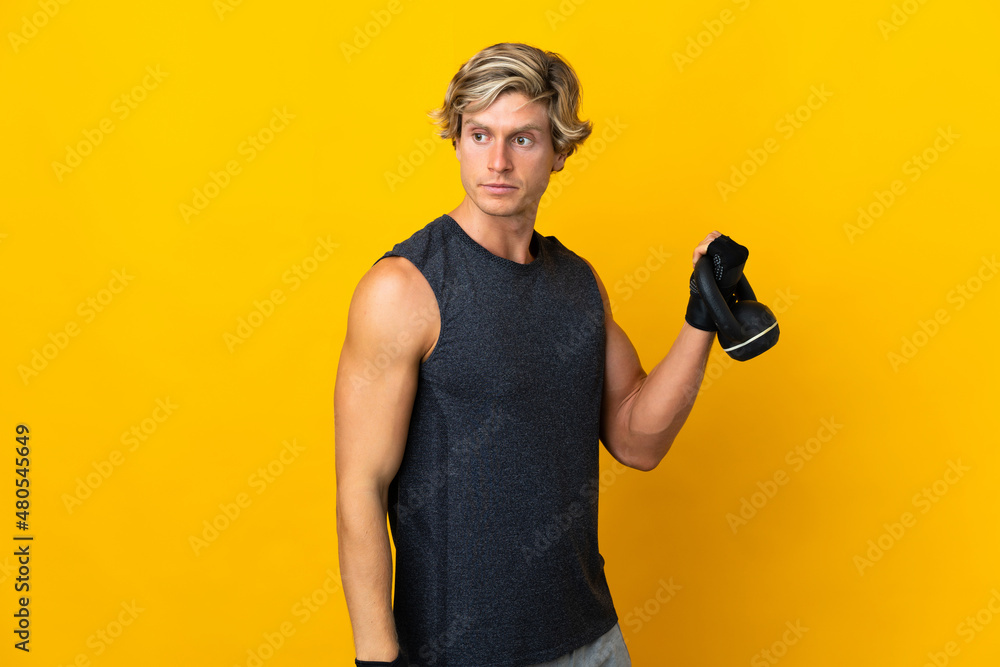 English man over isolated yellow background making weightlifting with kettlebell English man over isolated yellow background making weightlifting with kettlebell