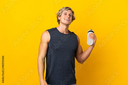 English man over isolated yellow background with sports water bottle © luismolinero
