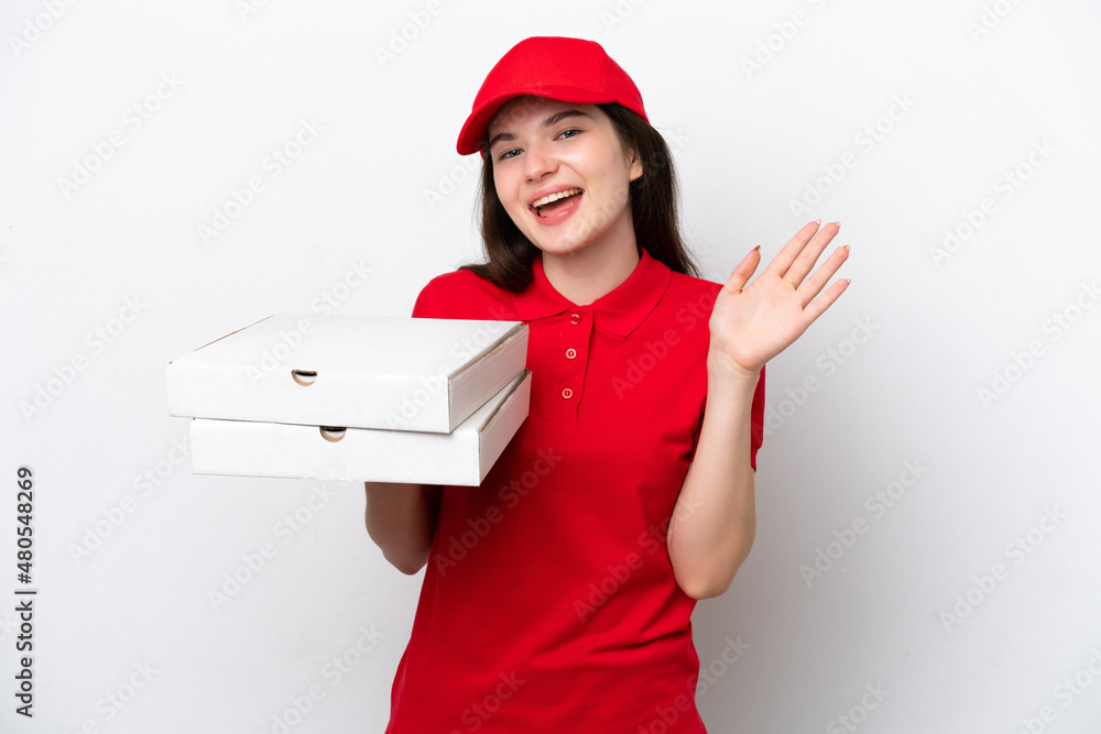 Young Russian pizza delivery picking up pizza boxes isolated on white background saluting with hand with happy expression Young Russian pizza delivery picking up pizza boxes isolated on white background saluting with hand with happy expression
