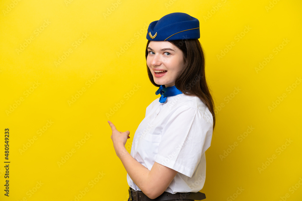 Airplane stewardess Russian woman isolated on yellow background pointing back Airplane stewardess Russian woman isolated on yellow background pointing back