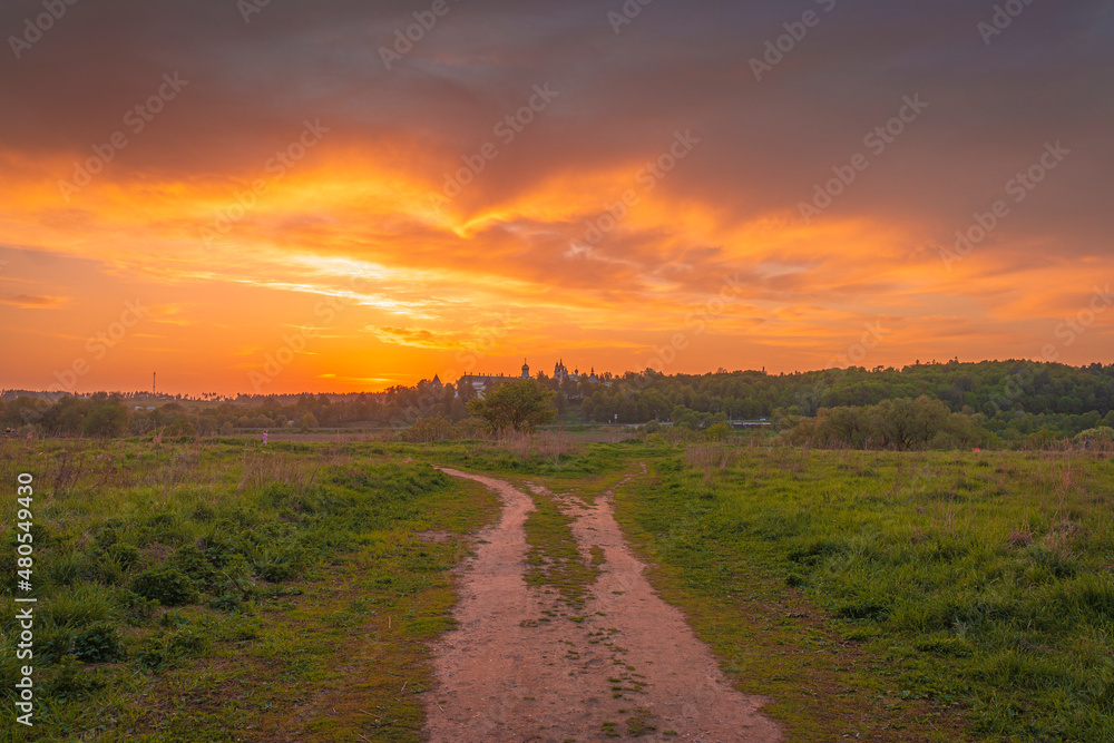 Wide angle view of the dirt road leading to Savvino-Storozhevskiy Monastyr' (Convent) with dramatic clouds at autumn sunset 