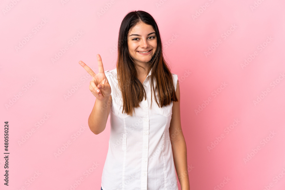Young caucasian woman isolated on pink background smiling and showing victory sign Young caucasian woman isolated on pink background smiling and showing victory sign