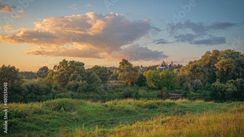 Autumn landscape with forest and old monastery at sunset