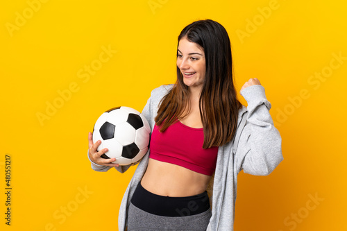 Young caucasian woman isolated on yellow background with soccer ball celebrating a victory © luismolinero
