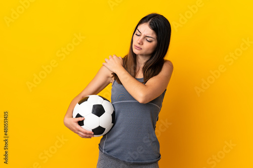 Young football player woman isolated on yellow background suffering from pain in shoulder for having made an effort © luismolinero