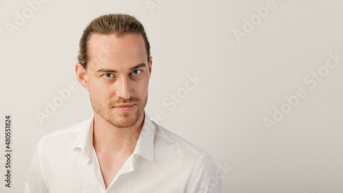 Young blonde bearded man looking in camera. Portrait of caucasian guy with trendy hairdo isolated over a white studio background with copy space