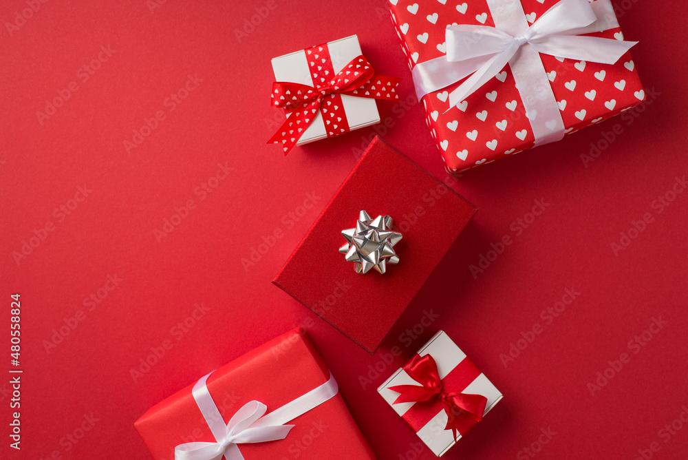 Top view photo of saint valentine's day decorations red giftbox with silver star bow red and white present boxes on isolated red background with blank space Top view photo of saint valentine's day decorations red giftbox with silver star bow red and white present boxes on isolated red background with blank space