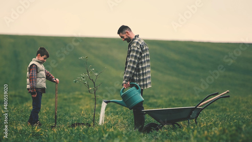 The dad and son watering a new tree