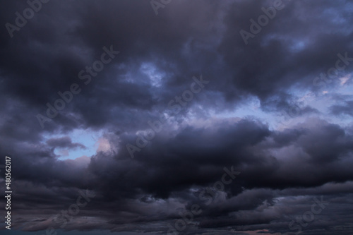 Epic Dramatic storm dark grey cumulus rain clouds against blue sky background texture, thunderstorm