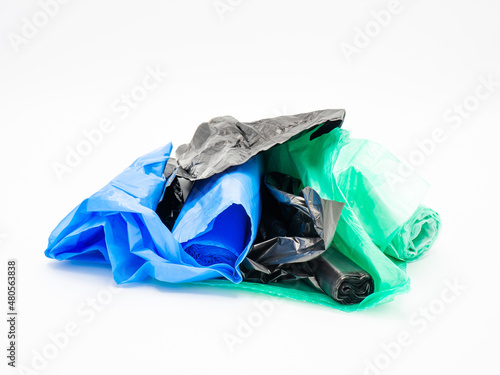 Colorful plastic trash bags rolled up, white background