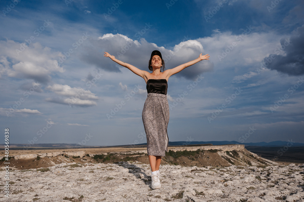 A female tourist standing with her hands up on the top. The girl greets the sun. A female tourist standing with her hands up on the top. The girl greets the sun.