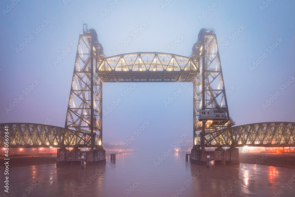 Disused railway bridge across a harbor in Rotterdam on a misty winter morning