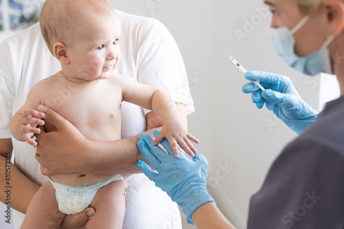 Pediatrician makes vaccination to small boy photo