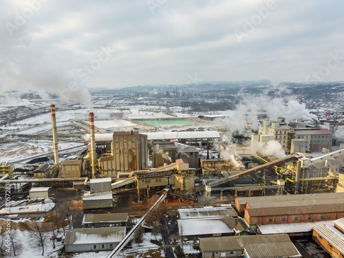 Aerial drone view of chimneys in factory blowing pollution in environment. Industrial air pollution from smokestacks. Toxic smoke from chimney in industrial area during winter. Industry complex.