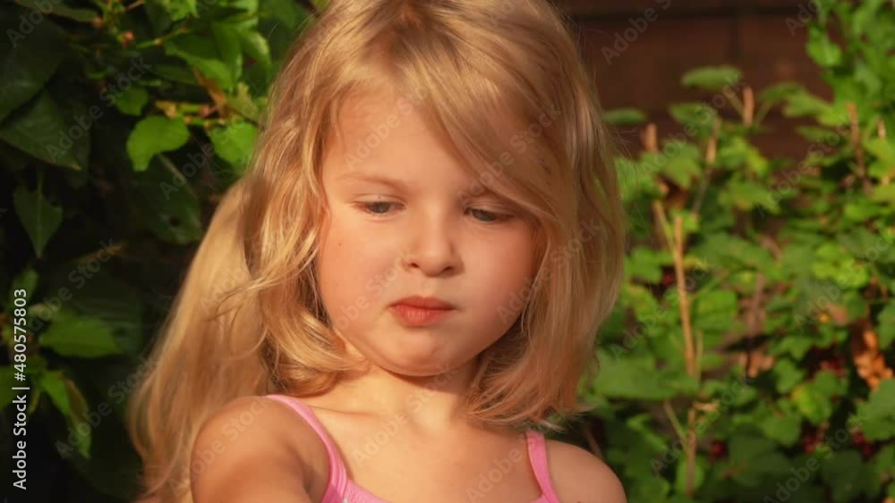 Blond girl is eating currant and smiling at camera Blond girl is eating currant and smiling at camera