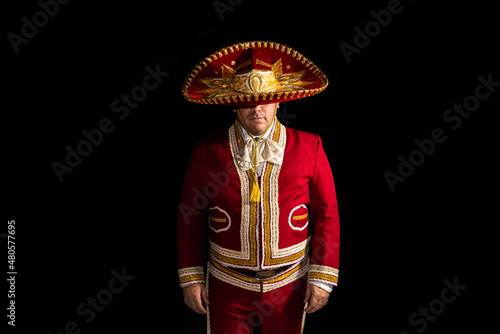 Mexican mariachi musician covering half of his face with a sombrero on a black background photo